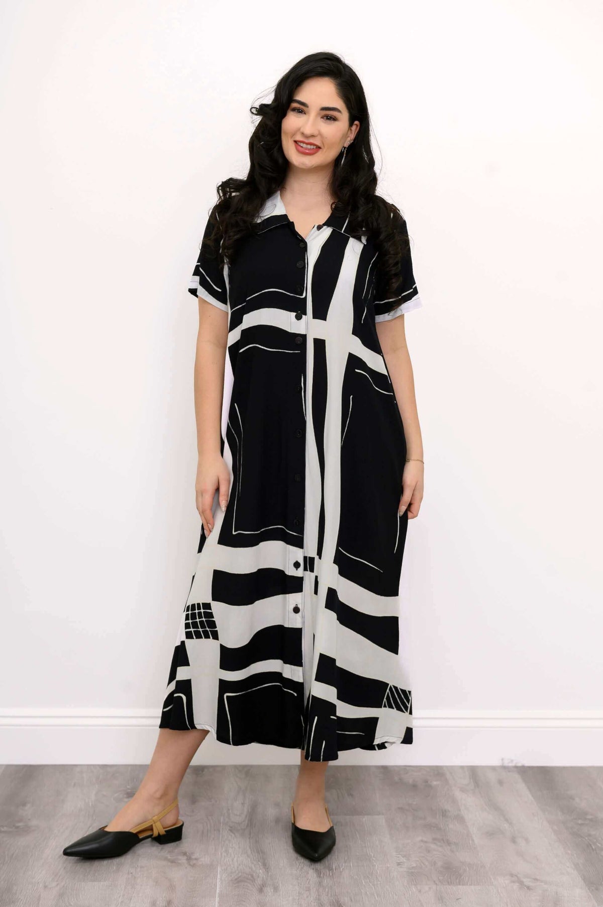 Woman standing in front view, wearing short sleeve black and white patterned shirt dress