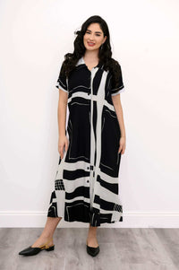 Woman standing in front view, wearing short sleeve black and white patterned shirt dress