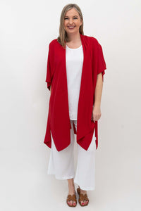 Woman wearing a vibrant red kimono wrap as an open layer over white outfit, front view
