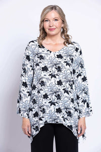 Front view of woman wearing a black and white floral flowy top with V-neck and bell sleeves
