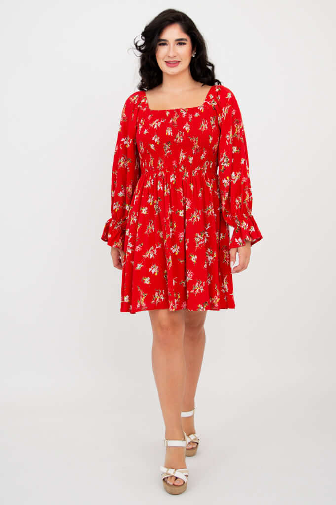 Front view of a model wearing a red ditsy print dress with long sleeves and square neckline