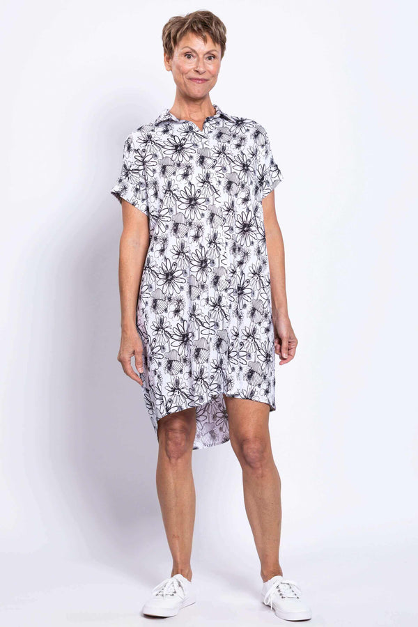 Front view of a woman wearing a black and white floral shirt dress with cuffed sleeves