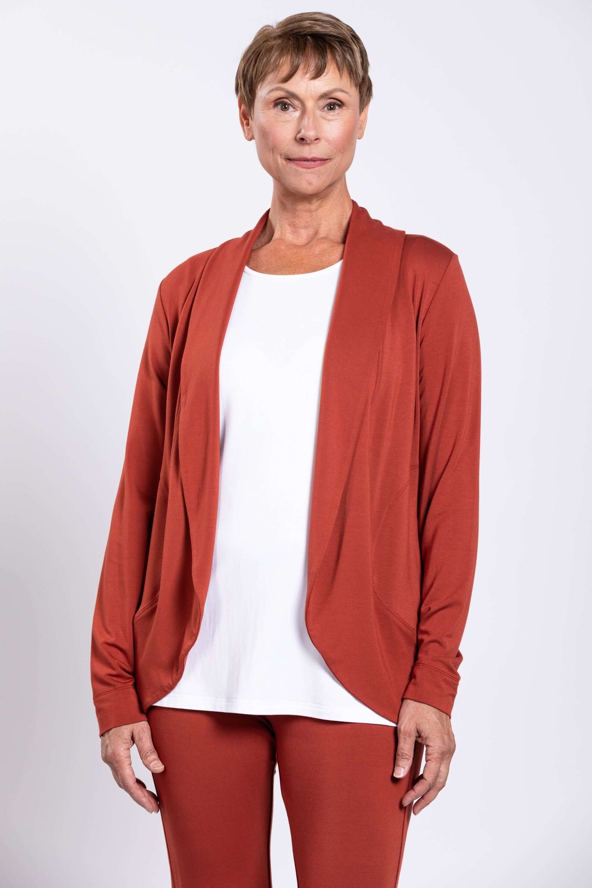 Front view of woman wearing rust-colored French Terry open front shawl collar jacket