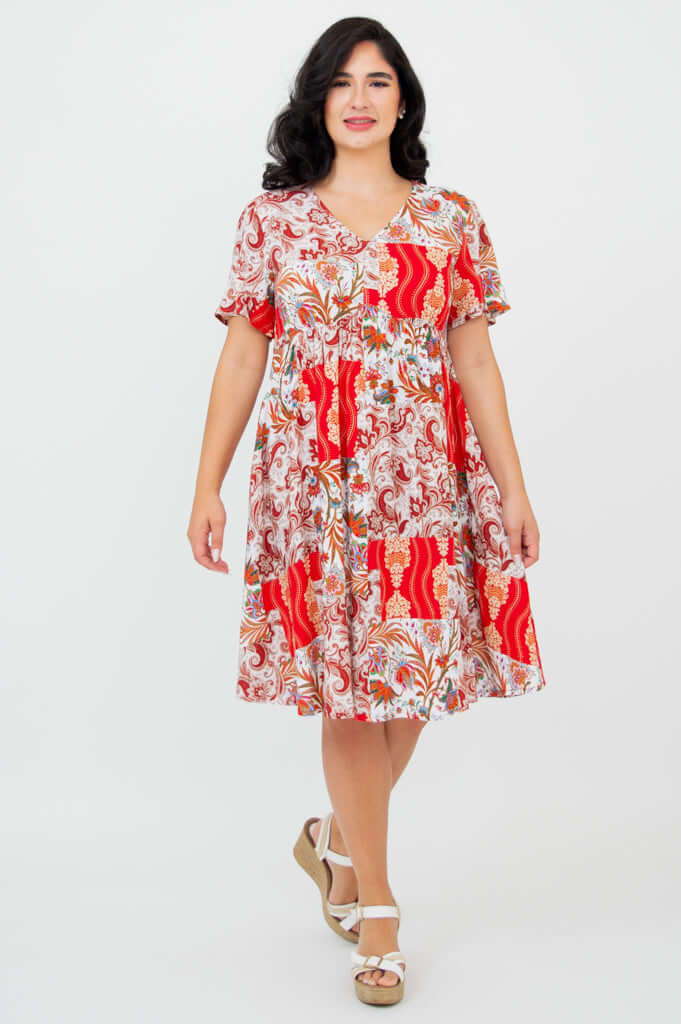 Model wearing a red and white floral empire waist dress with flutter sleeves, front view
