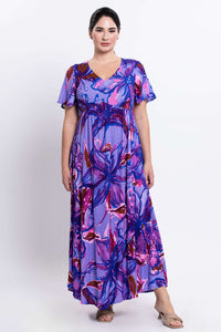 Front view of a woman wearing a flowing purple floral maxi dress with flutter sleeves