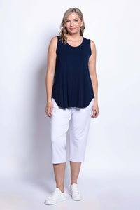 Woman wearing a navy bamboo tank top and white cropped pants, front view