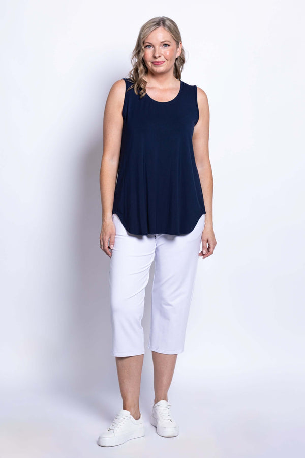 Woman wearing a navy bamboo tank top and white cropped pants, front view