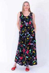 Front view of woman wearing a black bamboo maxi dress with vibrant floral print and red sandals