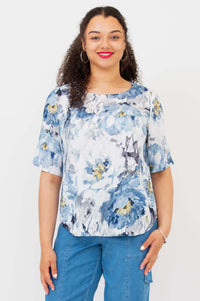 Front view of a woman wearing a blue and white floral blouse with elbow-length sleeves