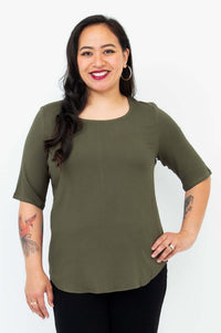 Front view of a woman wearing an olive green blouse with elbow length sleeves and a rounded neckline