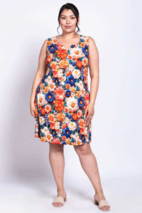 Front view of a woman wearing a sleeveless dress with vibrant orange, blue, and cream floral print