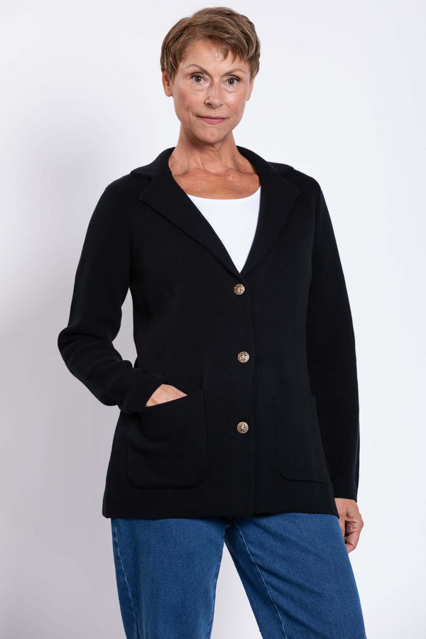 Front view of a woman wearing the black Margaret Jacket with patch pockets and gold buttons
