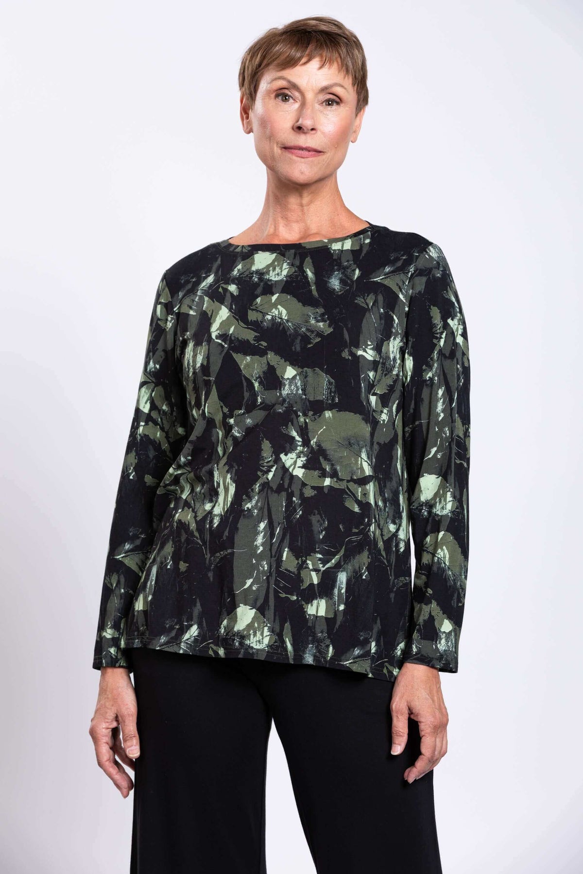 Front view of woman wearing black and green abstract print boat neck top