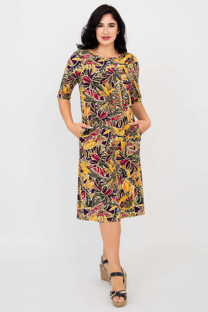 Front view of woman wearing colorful Olivia dress in Tropikal print with hands in pockets