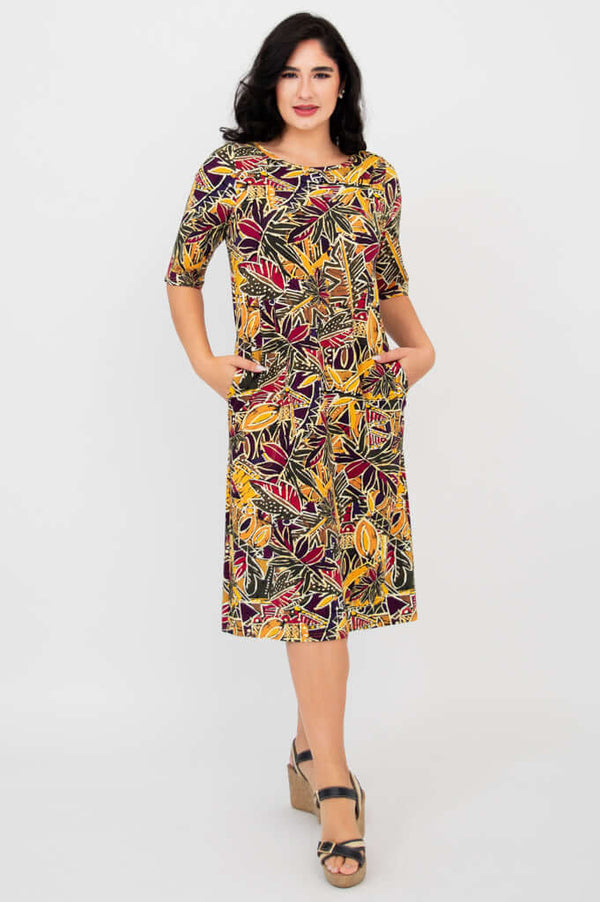 Front view of woman wearing colorful Olivia dress in Tropikal print with hands in pockets