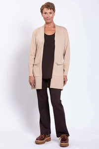 Front-facing woman in beige cardigan layered over a brown shirt and dark pants
