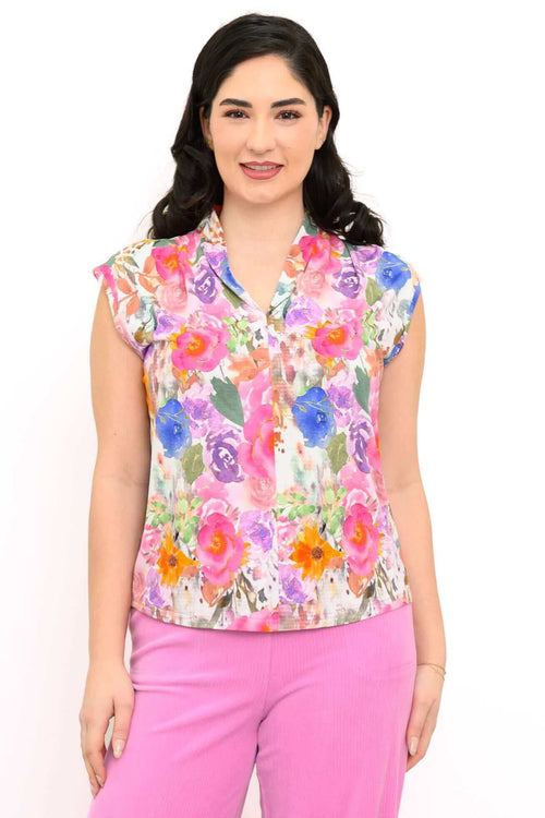 Front view of a woman wearing a vibrant floral sleeveless top with shawl collar