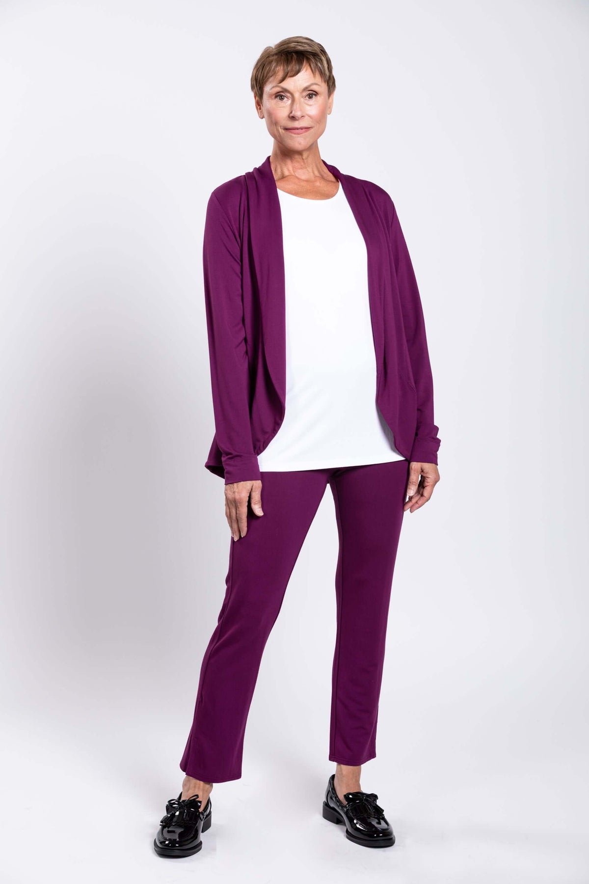 Front view of model wearing plum-colored slim bamboo pants and matching cardigan