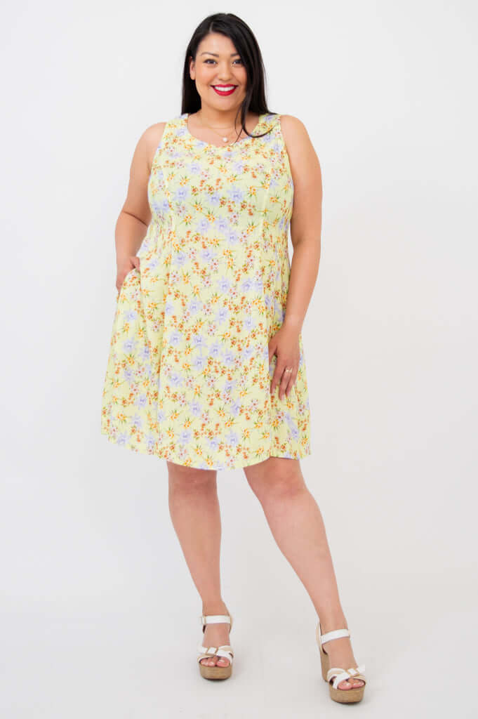 Woman in a sleeveless yellow floral dress with A-line silhouette and wedge sandals