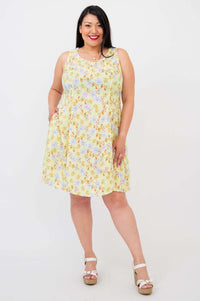 Woman in a sleeveless yellow floral dress with A-line silhouette and wedge sandals