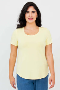 Front view of a woman wearing a light yellow scoop neck tee and blue pants
