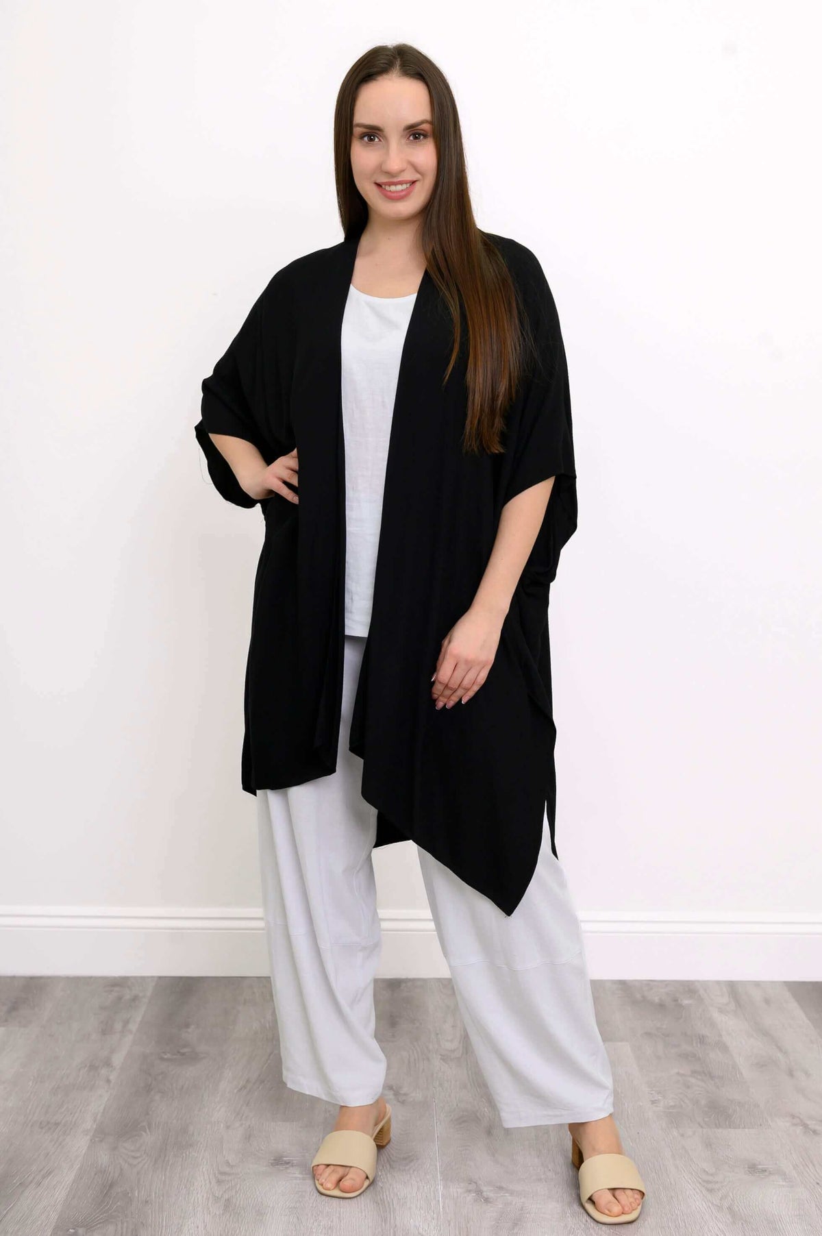 Front view of woman wearing a black Darcy kimono wrap over white outfit