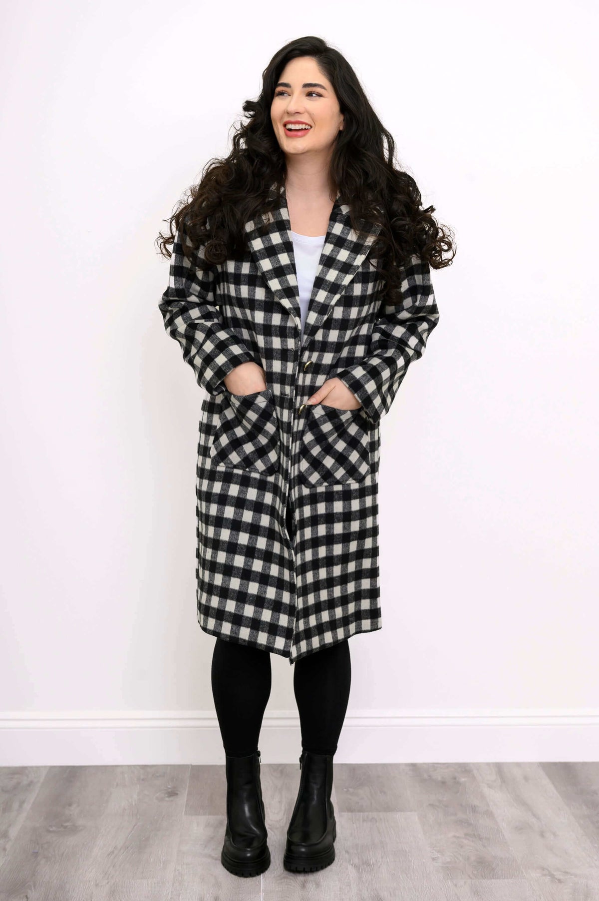 Front view of model wearing black and white check patterned coat with patch pockets