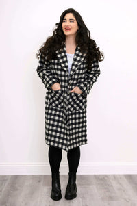 Front view of model wearing black and white check patterned coat with patch pockets