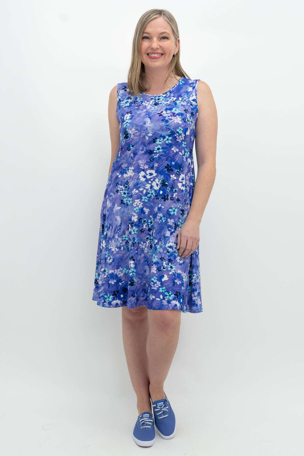 Woman wearing a sleeveless blue floral Willow dress, smiling, front view