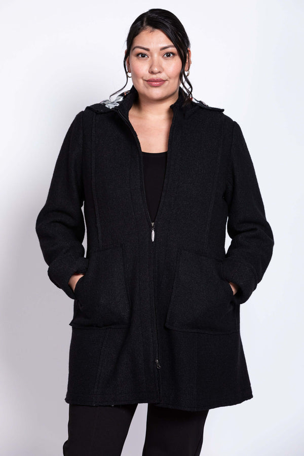 Front view of model wearing a black boiled wool car coat with detachable hood