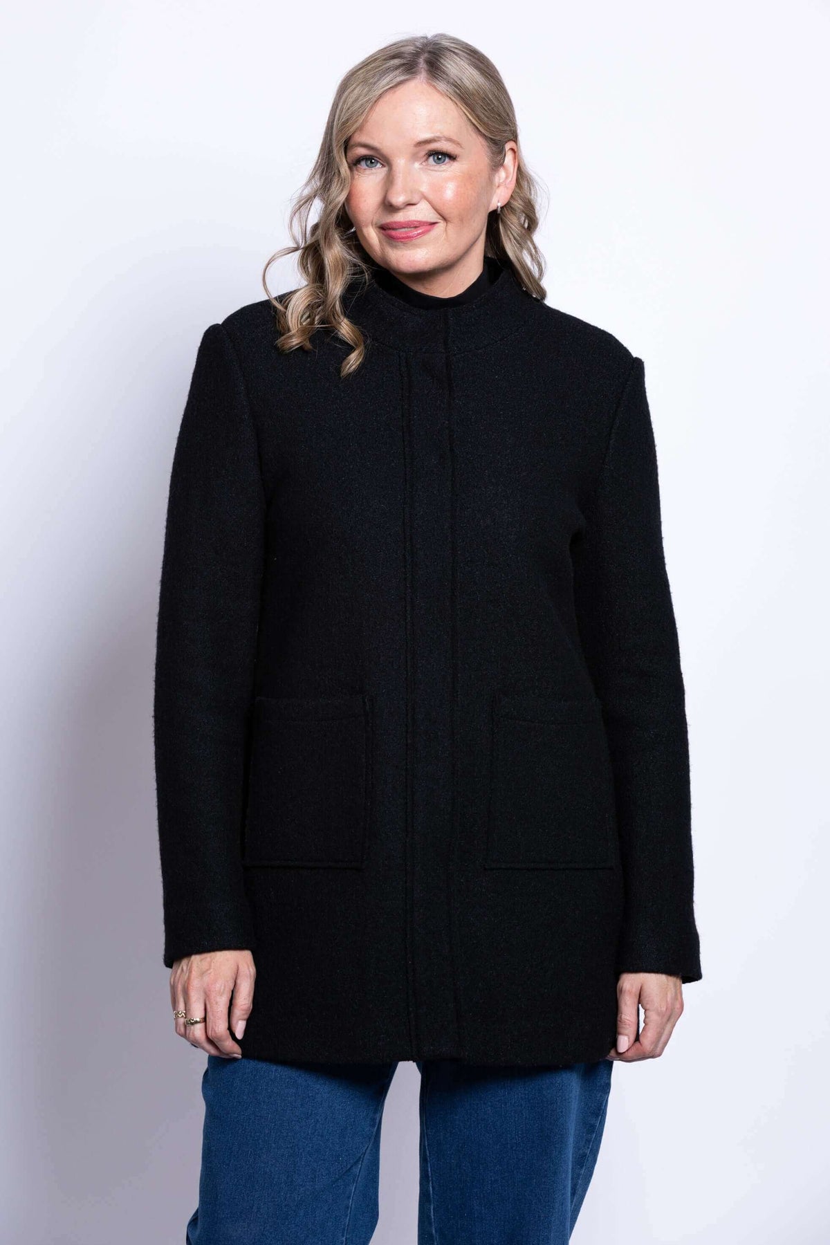 Front view of woman wearing a black boiled wool coat with mandarin collar