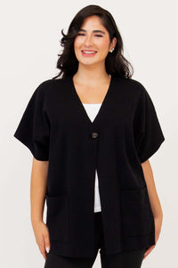 Front view of woman wearing a black cotton cardigan with cropped sleeves and large pockets