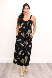Woman wearing a black wide-leg jumpsuit with tan feather print, standing and facing forward