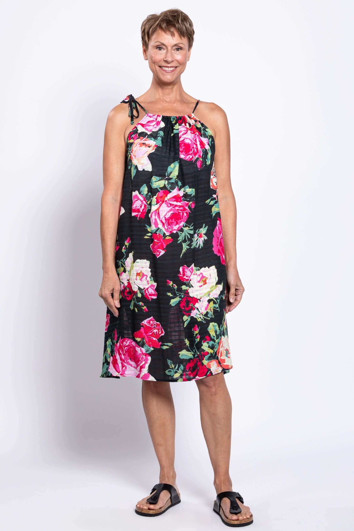 Front view of woman wearing black sleeveless floral beach dress with tie shoulder