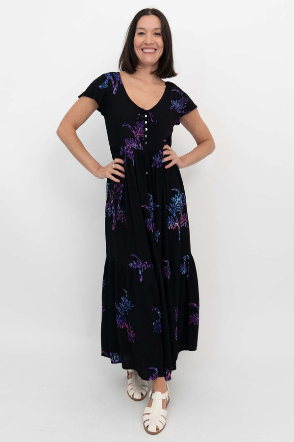 Front view of woman wearing a black maxi dress with purple and blue botanical print