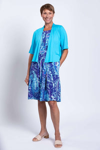 Front view of woman in blue Roam dress styled with turquoise cardigan