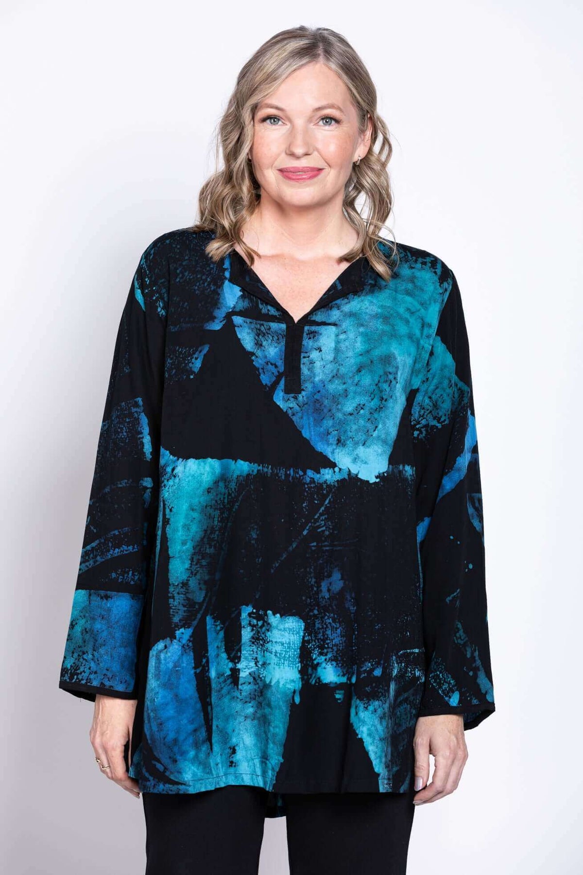 Front view of model wearing a blue and black batik print blouse with collared V-neck