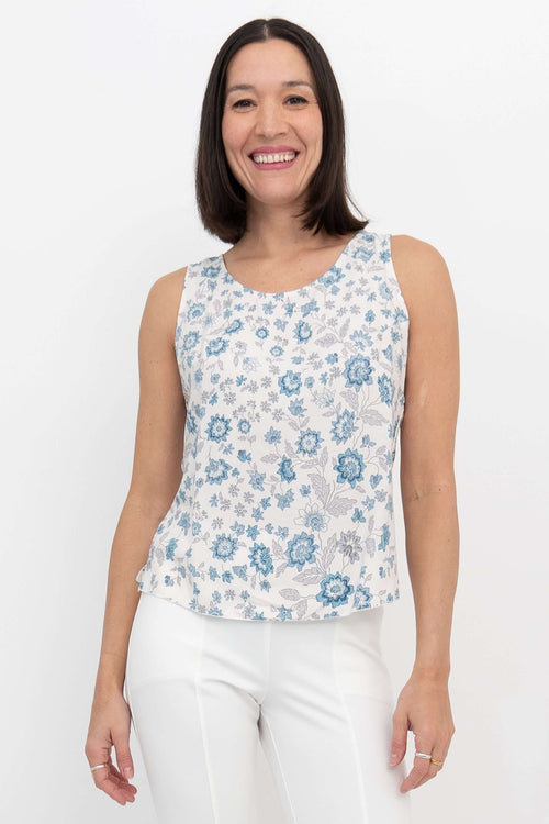 Woman wearing a sleeveless white tank top with blue floral print, front view