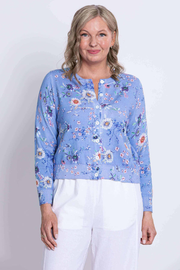 Front view of a woman wearing a blue floral button-up cardigan and white pants