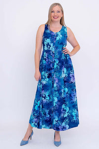 Front view of a woman in a blue floral sleeveless maxi dress, hand on hip and smiling