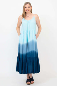 Front view of a woman wearing a light blue to navy ombre maxi dress with adjustable straps and pockets