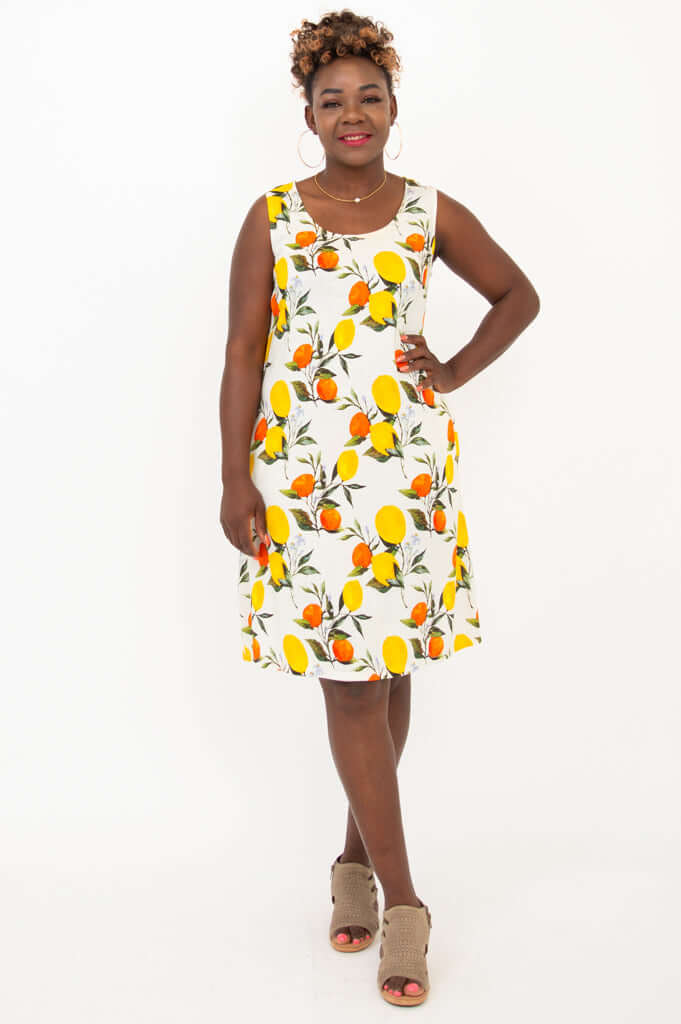 Front view of woman wearing a sleeveless shift dress with lemon and orange print