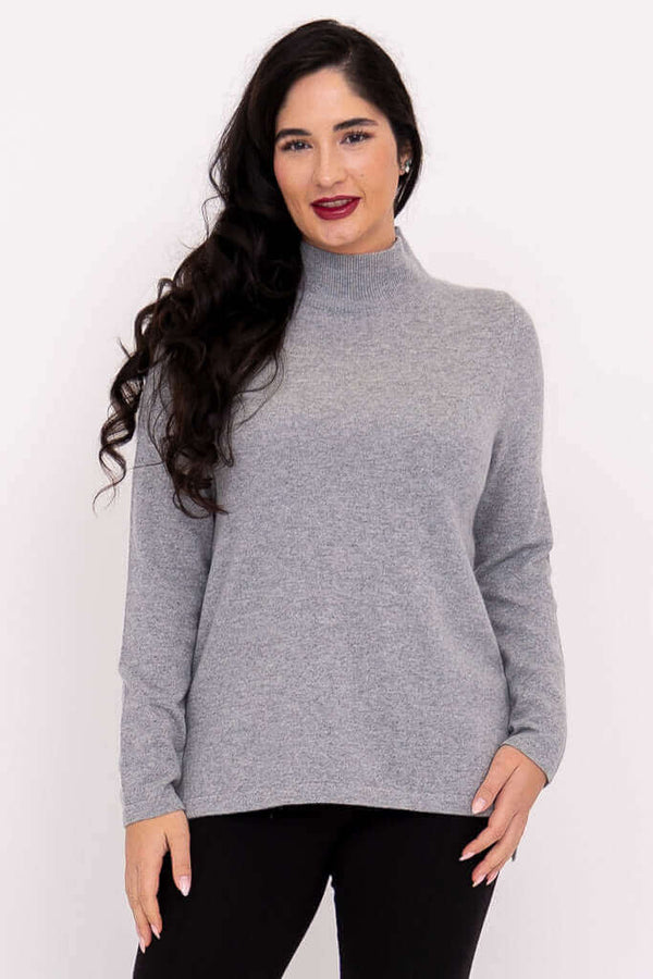 Front view of a woman wearing a grey mock neck sweater with long sleeves and black pants