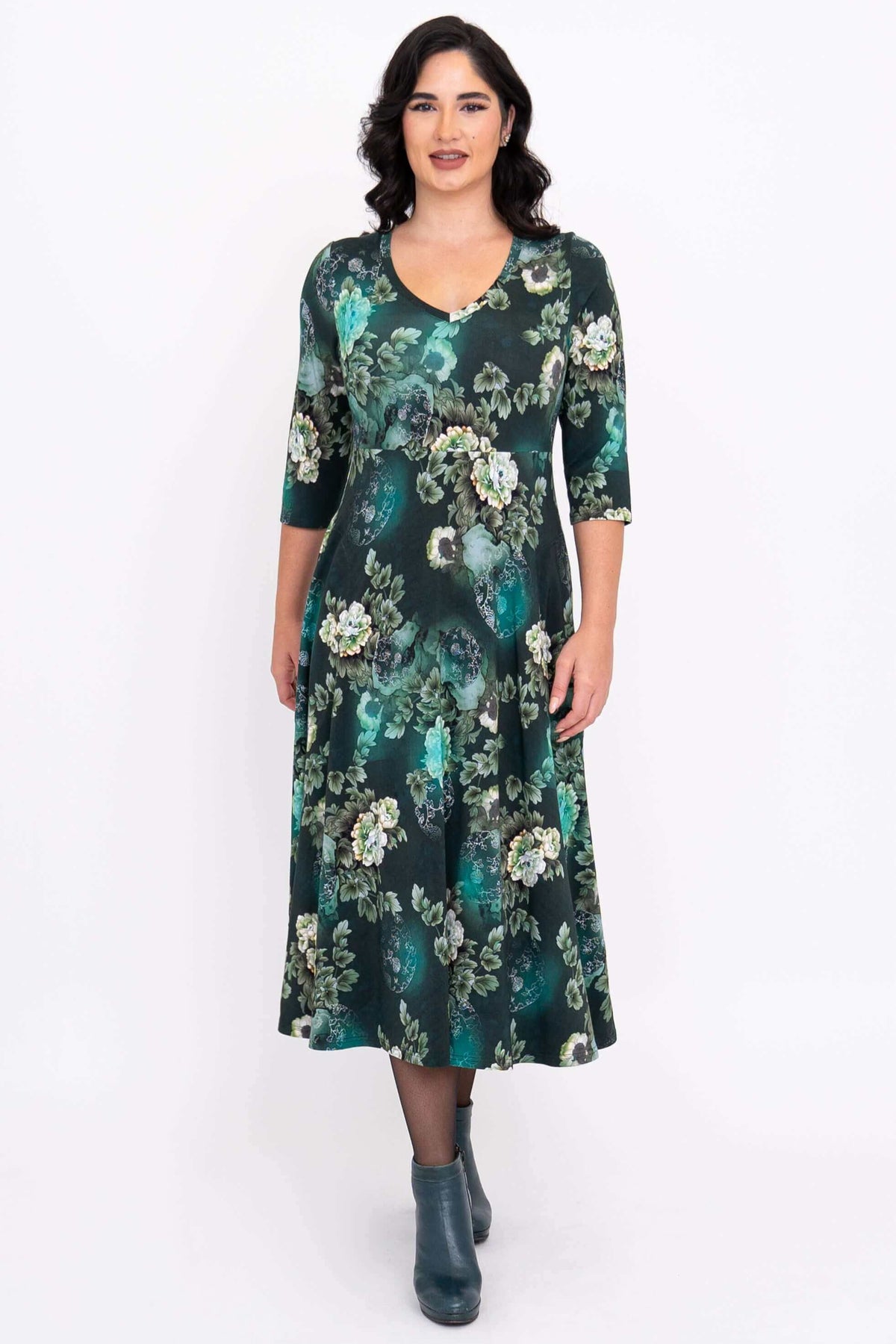 Front view of a woman wearing a jade green floral midi dress with empire waist