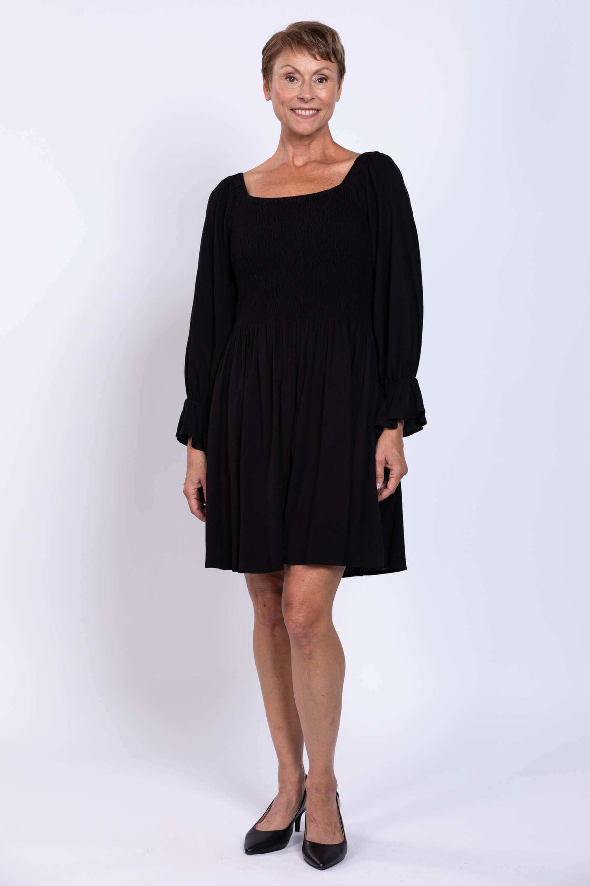 Front view of black knee-length dress with square neckline and shirred bodice
