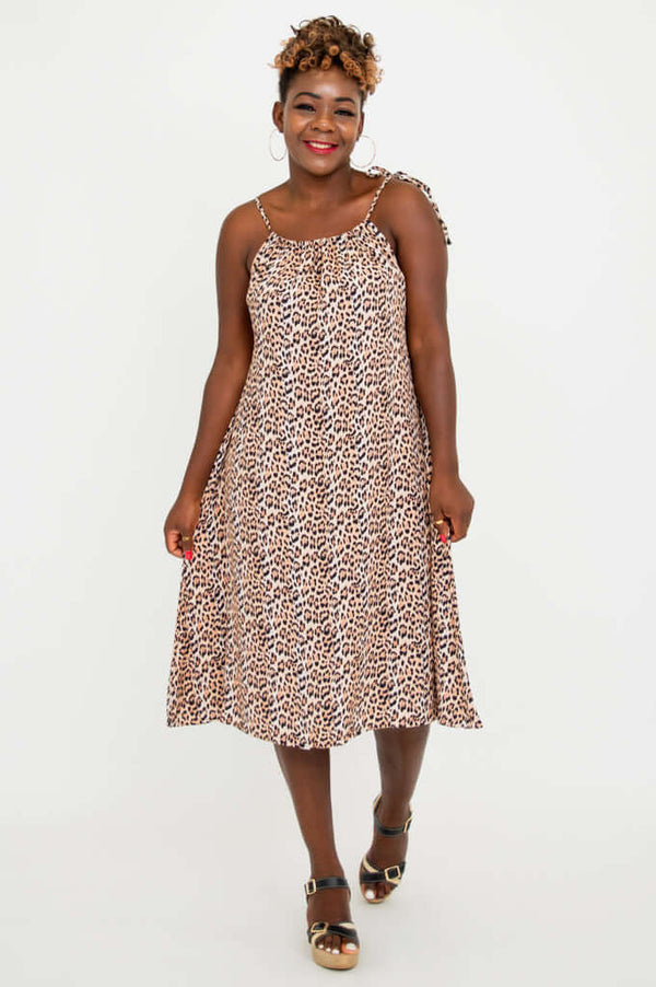 Front view of woman wearing a sleeveless leopard print knee-length dress with tie shoulder