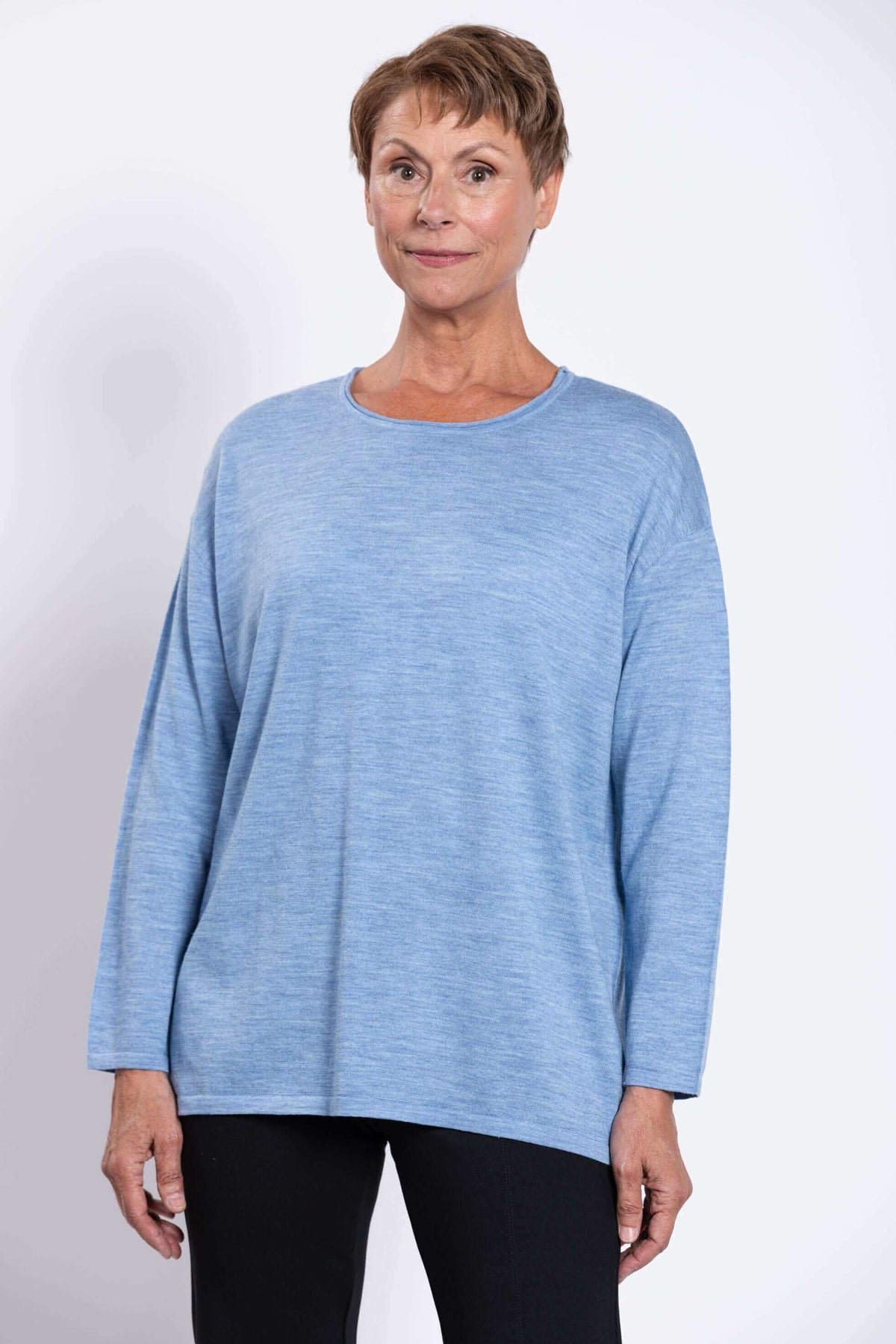 Front view of a woman wearing a light blue merino wool pullover sweater with black pants