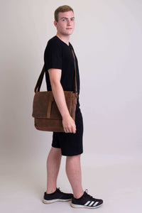 Man facing forward carrying a brown buffalo leather messenger bag with adjustable strap