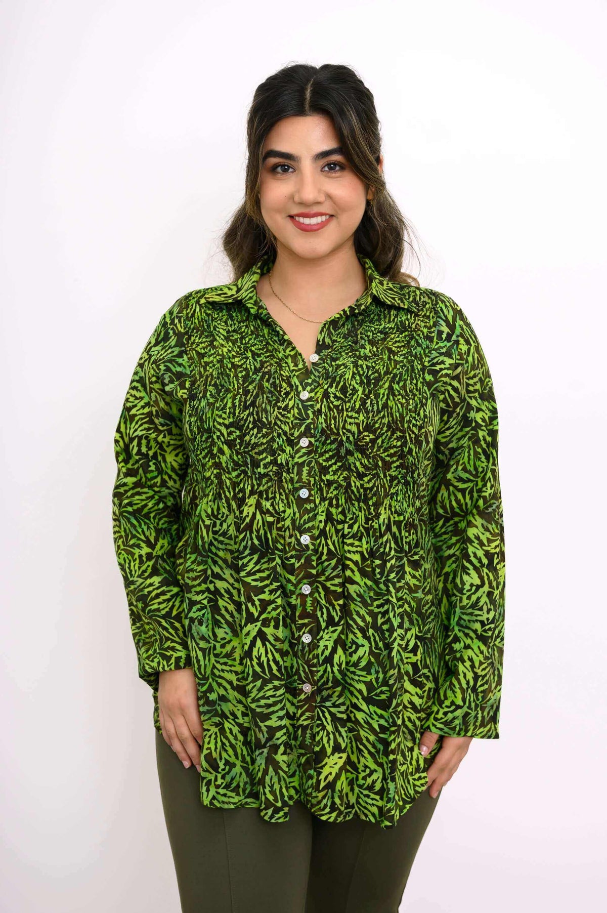 Model in green leaf print shirt smiling, shown from the front