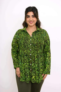 Model in green leaf print shirt smiling, shown from the front
